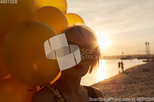 Image of Young woman with many golden balloons.