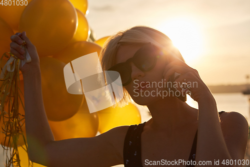 Image of Young woman with many golden balloons.