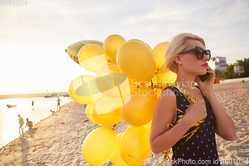 Image of Young woman with many golden balloons.