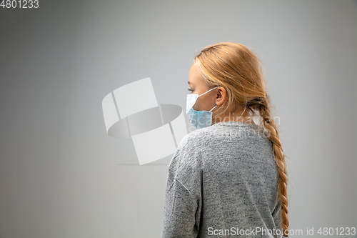 Image of Caucasian girl wearing the respiratory protection mask against air pollution and dusk on grey studio background