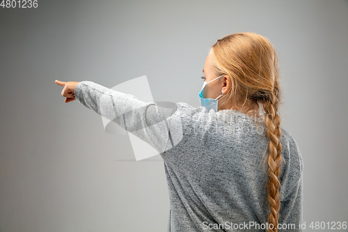 Image of Caucasian girl wearing the respiratory protection mask against air pollution and dusk on grey studio background