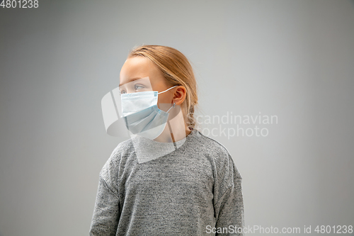 Image of Caucasian girl wearing the respiratory protection mask against air pollution and dusk on grey studio background