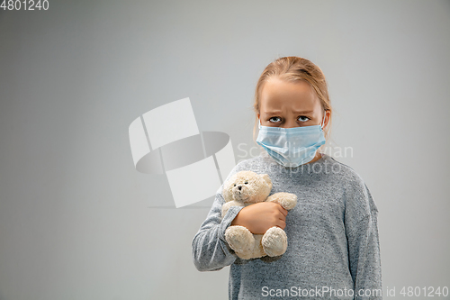 Image of Caucasian girl wearing the respiratory protection mask against air pollution and dusk on grey studio background