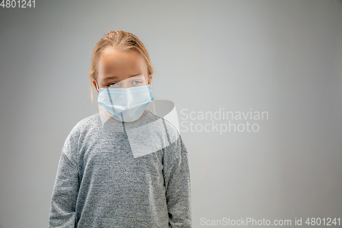 Image of Caucasian girl wearing the respiratory protection mask against air pollution and dusk on grey studio background