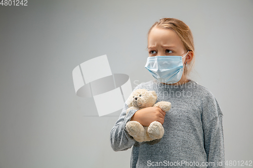 Image of Caucasian girl wearing the respiratory protection mask against air pollution and dusk on grey studio background