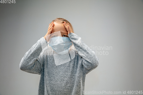 Image of Caucasian girl wearing the respiratory protection mask against air pollution and dusk on grey studio background