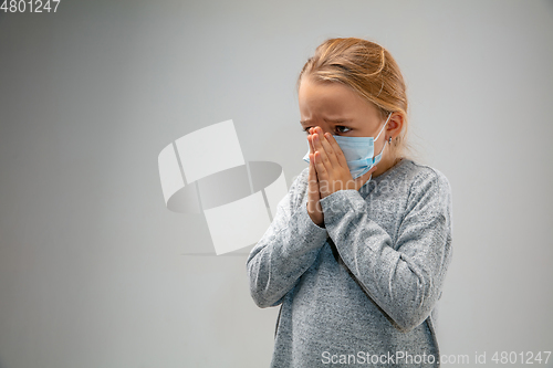 Image of Caucasian girl wearing the respiratory protection mask against air pollution and dusk on grey studio background