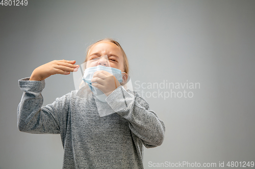 Image of Caucasian girl wearing the respiratory protection mask against air pollution and dusk on grey studio background