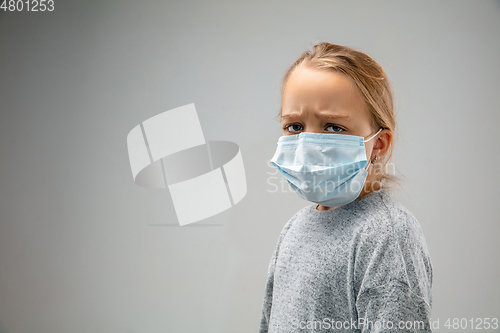 Image of Caucasian girl wearing the respiratory protection mask against air pollution and dusk on grey studio background