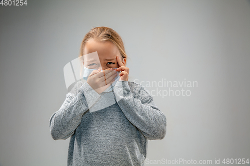 Image of Caucasian girl wearing the respiratory protection mask against air pollution and dusk on grey studio background