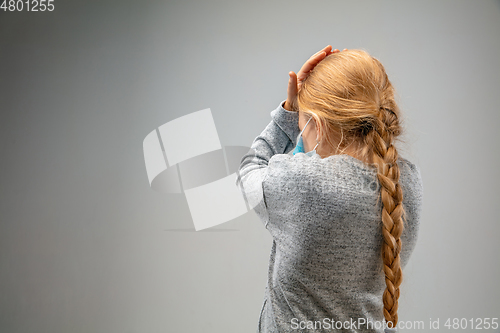 Image of Caucasian girl wearing the respiratory protection mask against air pollution and dusk on grey studio background