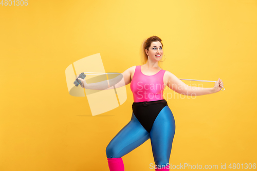 Image of Young caucasian plus size female model\'s training on yellow background