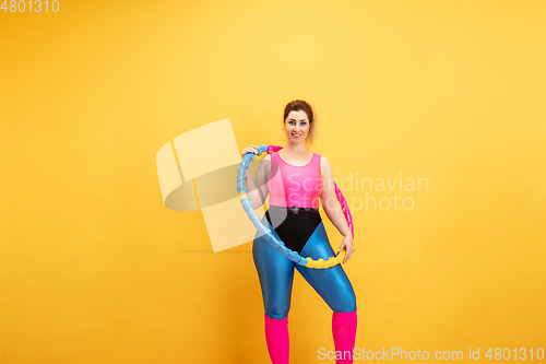 Image of Young caucasian plus size female model\'s training on yellow background