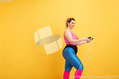 Image of Young caucasian plus size female model\'s training on yellow background