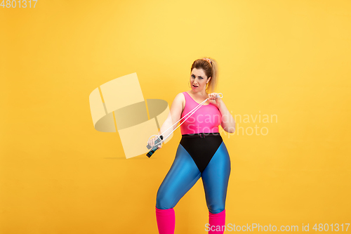 Image of Young caucasian plus size female model\'s training on yellow background