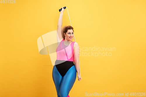 Image of Young caucasian plus size female model\'s training on yellow background