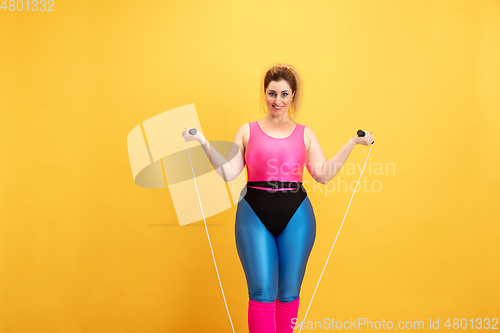 Image of Young caucasian plus size female model\'s training on yellow background