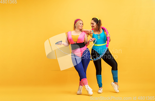 Image of Young caucasian plus size female models training on yellow background