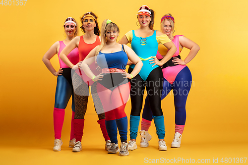 Image of Young caucasian plus size female models training on yellow background