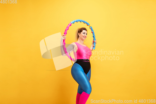 Image of Young caucasian plus size female model\'s training on yellow background