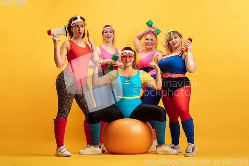 Image of Young caucasian plus size female models training on yellow background