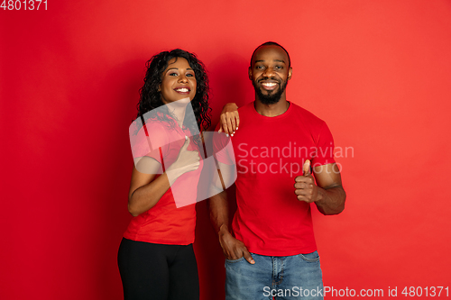 Image of Young emotional african-american man and woman on red background