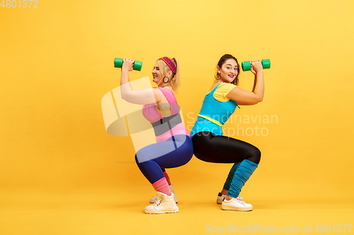Image of Young caucasian plus size female models training on yellow background