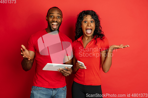 Image of Young emotional african-american man and woman on red background