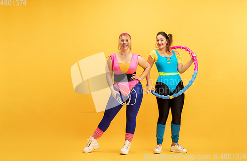 Image of Young caucasian plus size female models training on yellow background