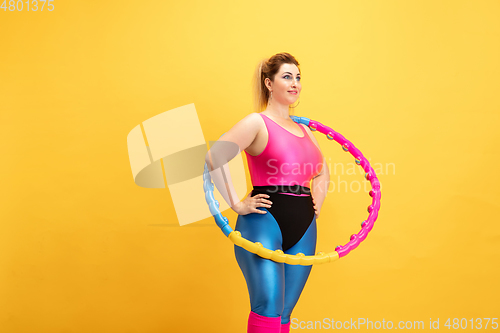 Image of Young caucasian plus size female model\'s training on yellow background