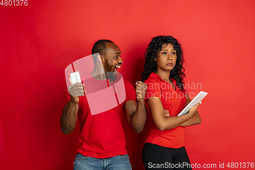 Image of Young emotional african-american man and woman on red background