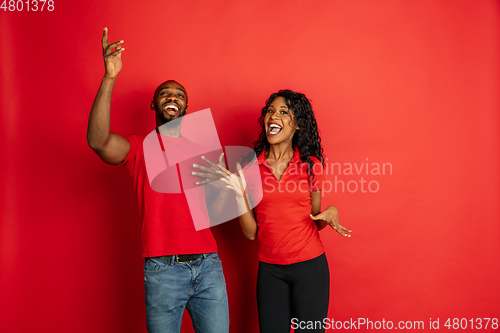 Image of Young emotional african-american man and woman on red background