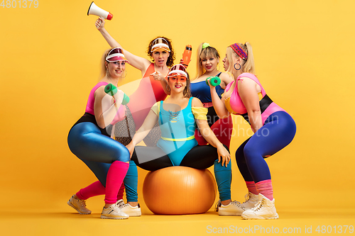 Image of Young caucasian plus size female models training on yellow background