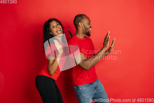 Image of Young emotional african-american man and woman on red background