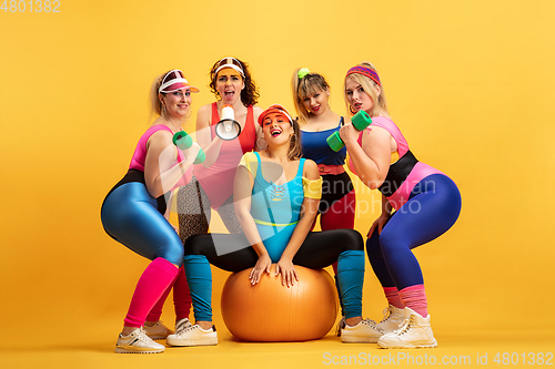 Image of Young caucasian plus size female models training on yellow background