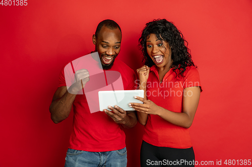 Image of Young emotional african-american man and woman on red background