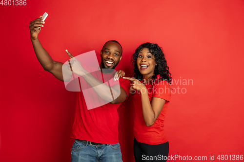 Image of Young emotional african-american man and woman on red background