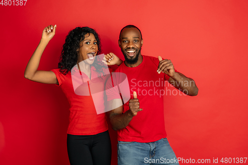 Image of Young emotional african-american man and woman on red background