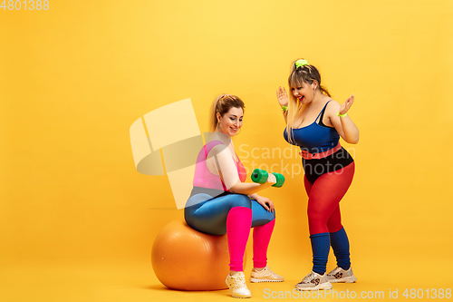 Image of Young caucasian plus size female models training on yellow background