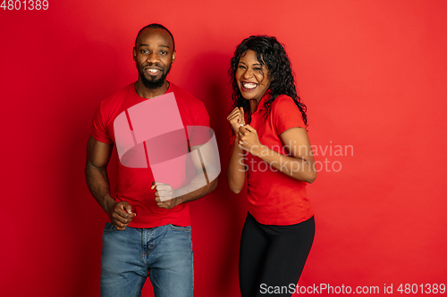 Image of Young emotional african-american man and woman on red background