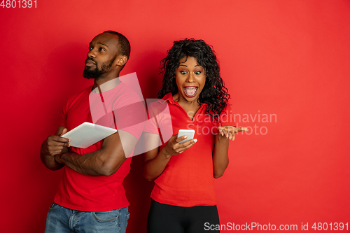 Image of Young emotional african-american man and woman on red background