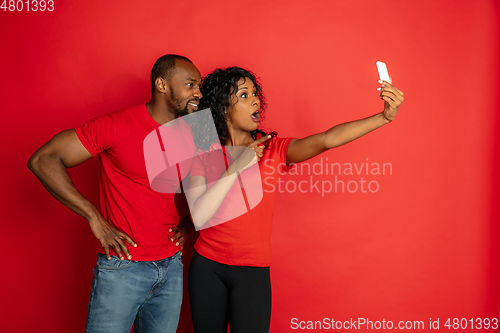 Image of Young emotional african-american man and woman on red background