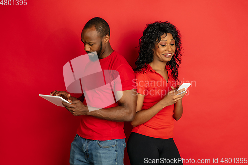 Image of Young emotional african-american man and woman on red background