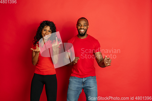 Image of Young emotional african-american man and woman on red background