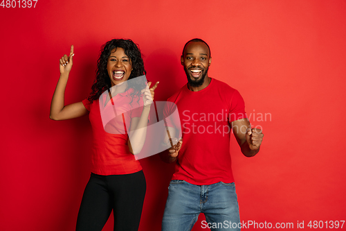 Image of Young emotional african-american man and woman on red background