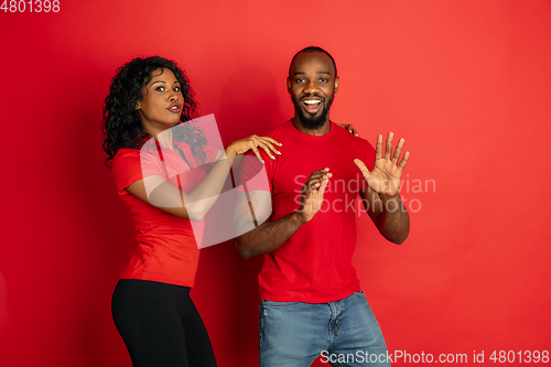 Image of Young emotional african-american man and woman on red background