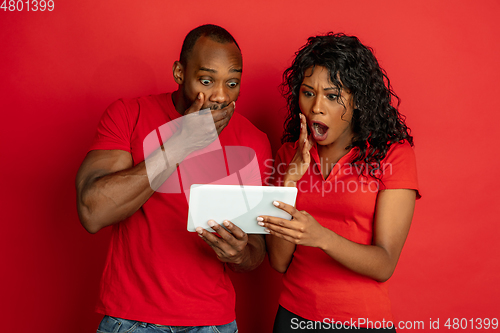 Image of Young emotional african-american man and woman on red background