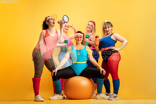 Image of Young caucasian plus size female models training on yellow background