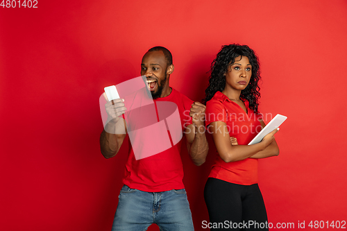 Image of Young emotional african-american man and woman on red background