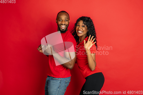 Image of Young emotional african-american man and woman on red background